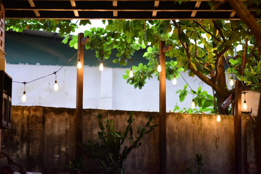 String lights strung between wooden posts over a backyard patio
